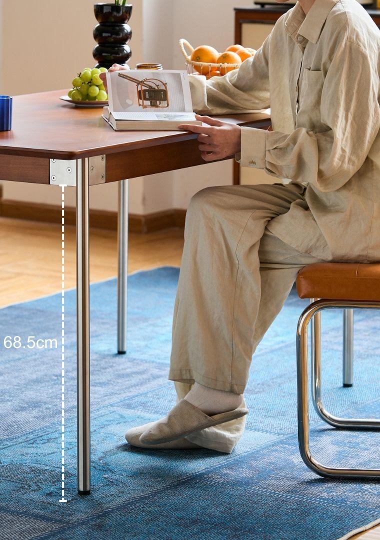 Person sitting at a table with a laptop, measuring the table&