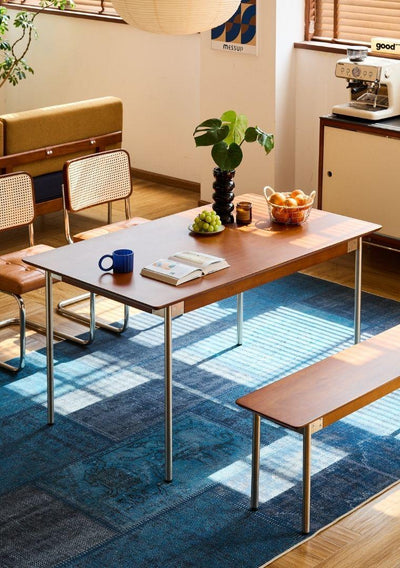 Dining area with a table, chairs, and a rug in a room.