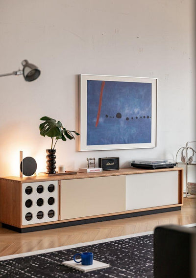 Modern living room with wooden console table, abstract art, and decorative items.