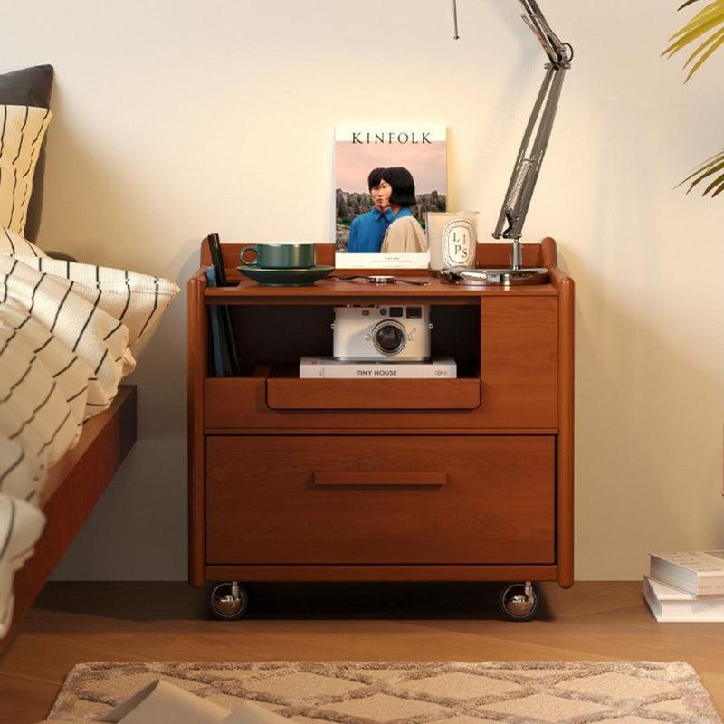 Wooden nightstand with books, a camera, and a lamp in a bedroom setting.
