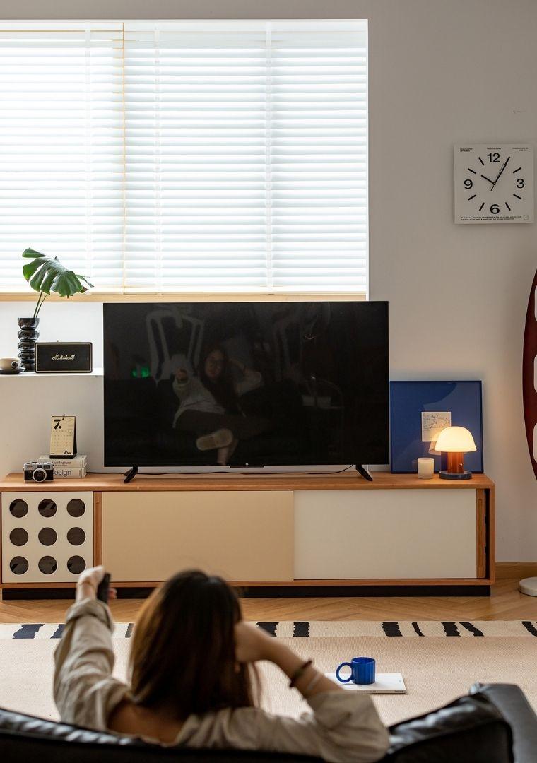 Person sitting on a couch in a living room watching TV.