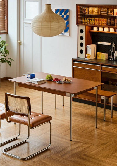 Dining area with wooden table, chairs, and a shelf in the background.