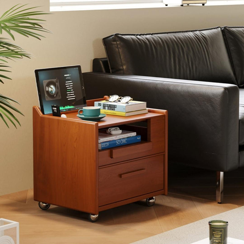 Wooden side table with laptop, books, and a cup next to a black leather sofa.