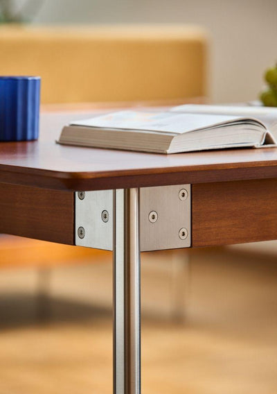 Wooden table with metal legs and a book on top, blurred background