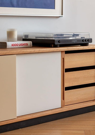 Wooden cabinet with a record player on top, featuring a book titled '1000 Lights'.