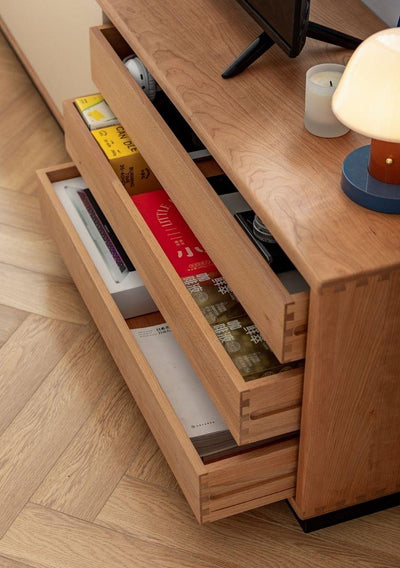 Wooden drawer with books and a lamp on a wooden floor