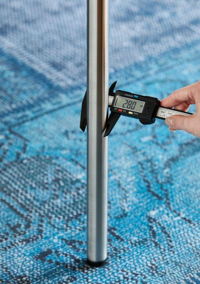 Digital caliper measuring a metal rod against a blue textured background