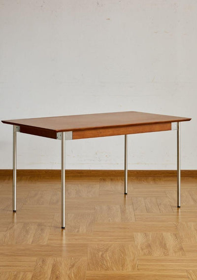 Wooden table with metal legs on a wooden floor against a white wall