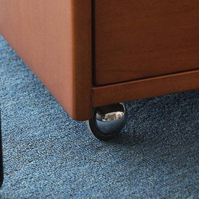 Close-up of a wooden drawer with a wheel on a blue carpet